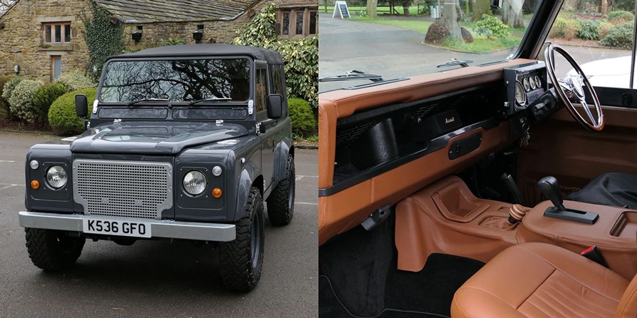 Classic dark grey Land Rover Defender with rugged tires.
