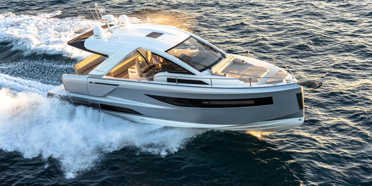 A sleek white luxury yacht cruising on the ocean at sunset.