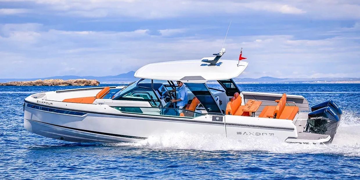 A sleek white motorboat with orange seats cruising on blue water.