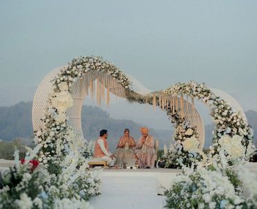 Elegant outdoor wedding ceremony with floral heart-shaped arch.
