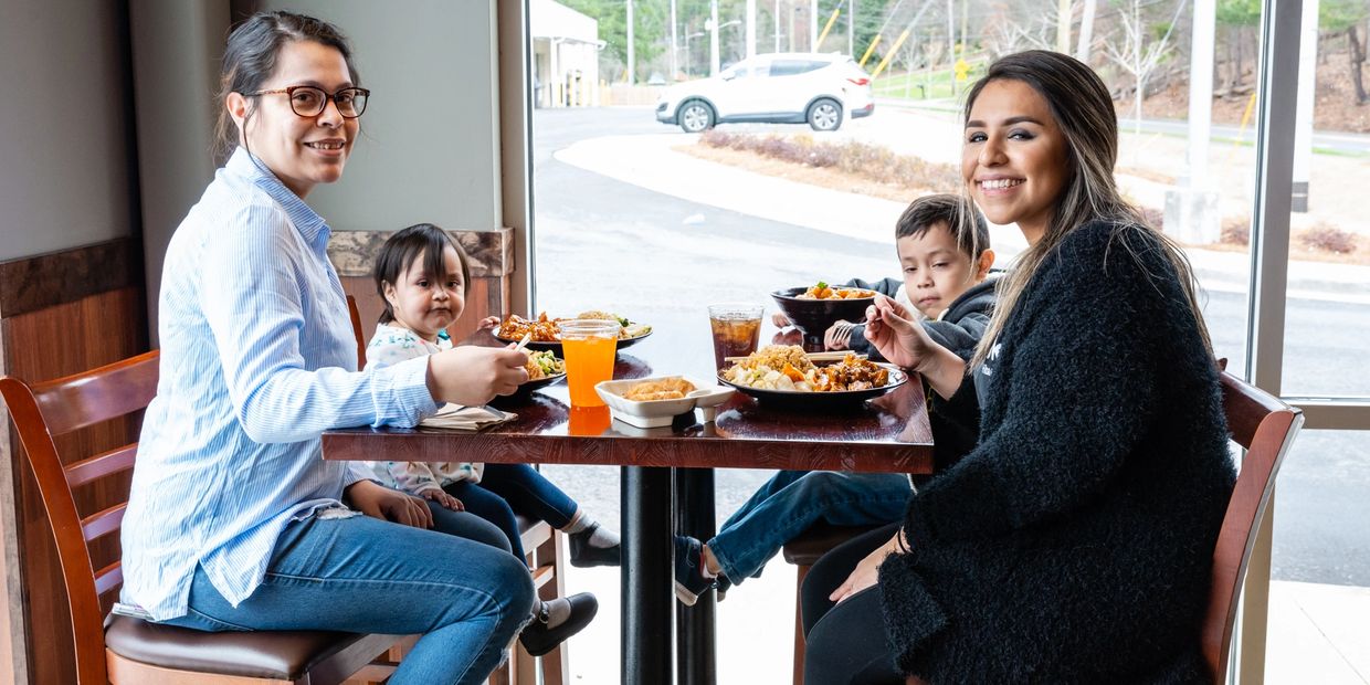 Two women enjoying food with their kids 