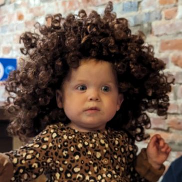 small baby with Bob Ross afro wig