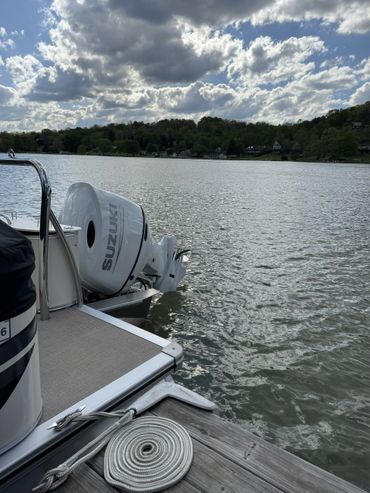 Boat motor by a dock on a cloudy day over a lake.