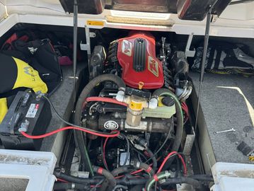 Boat engine compartment showing a red engine and connected battery.