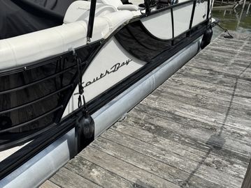 Black and white pontoon boat docked at a wooden pier.