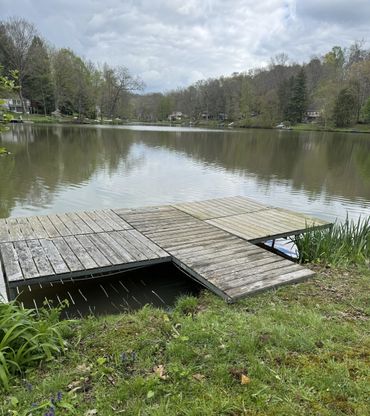 Wooden dock extending over a calm lake surrounded by trees.