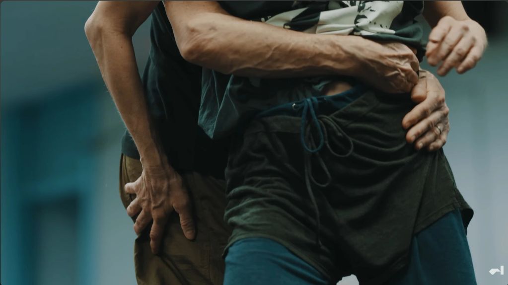 Close-up of two people practicing a wrestling or martial arts hold.
