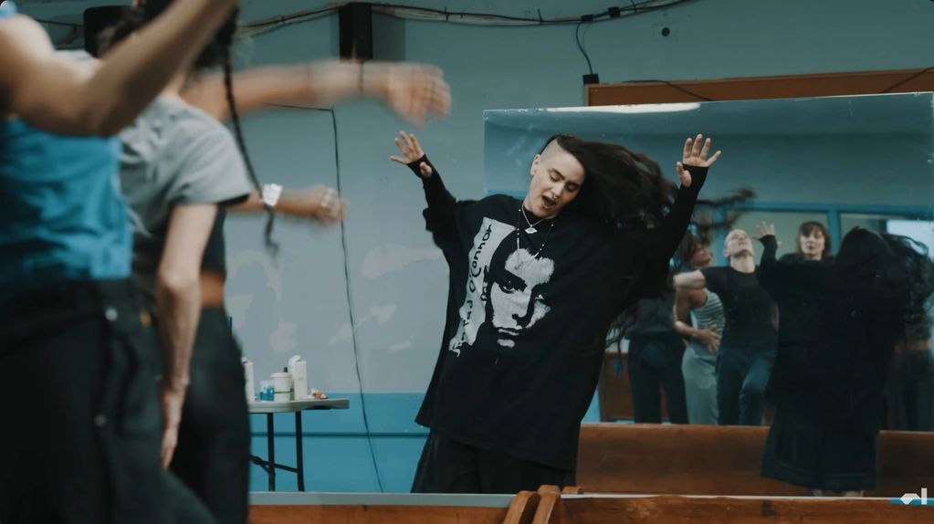 Person dancing excitedly in front of a mirror in a dance studio.