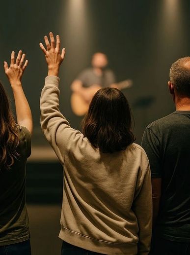 People raising hands during a live music performance in a dimly lit venue.