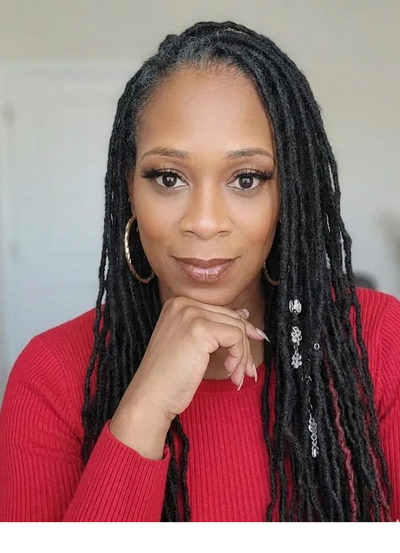 Confident woman with long dreadlocks and hoop earrings in a red sweater.