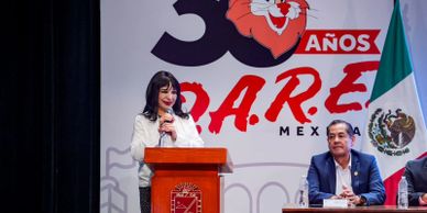 Woman speaking at a podium during a D.A.R.E. Mexico event.