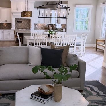Modern living room and kitchen with neutral tones and natural light.