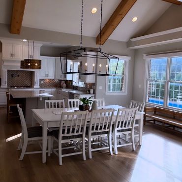 Bright dining area with white furniture and large windows.