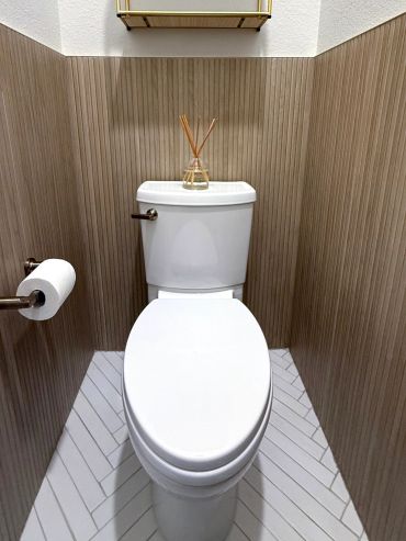 Clean toilet with reed diffuser and toilet paper.