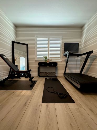 Home gym setup with bench, treadmill, and workout mat.