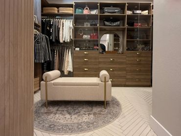 Elegant walk-in closet with bench and organized shelves.
