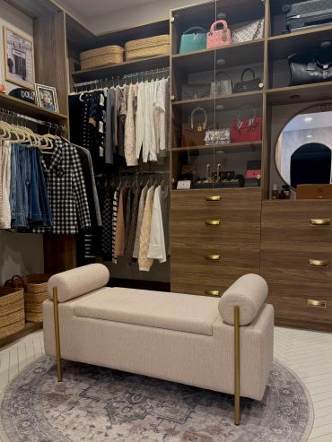 Elegant dressing room with bench and organized wardrobe.