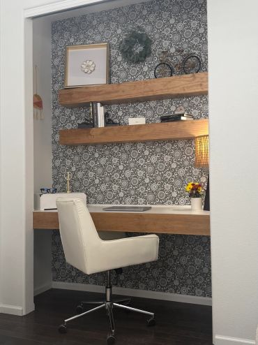 Cozy workspace with wooden shelves and patterned wallpaper.