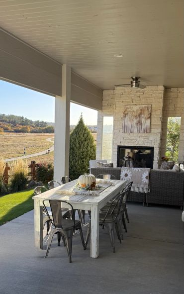 Cozy outdoor patio with dining table, chairs, and fireplace.