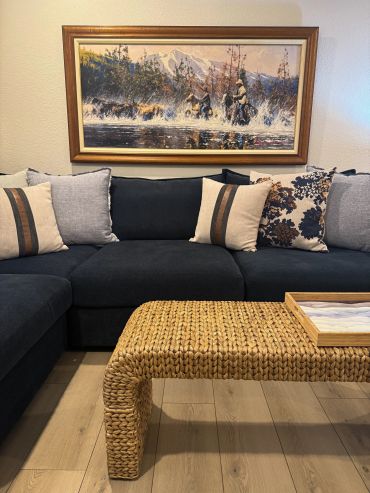 Cozy living room with dark sofa and woven coffee table.