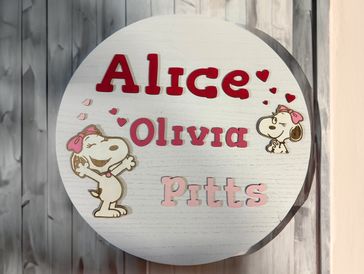 Decorative circular plaque with names and Snoopy characters.