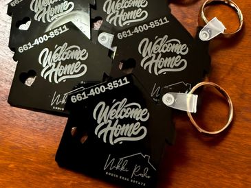 Keychains with "Welcome Home" text and real estate contact info.