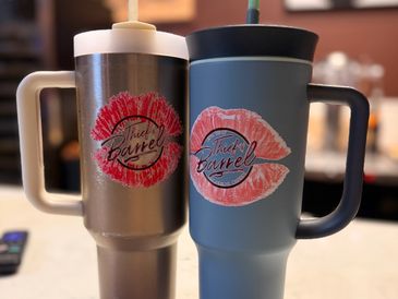 Two travel mugs with lipstick kiss marks and logos.