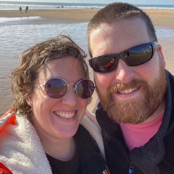 Smiling couple enjoying a sunny day at the beach with sunglasses.