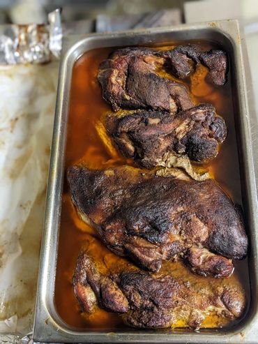 Tray of cooked, seasoned meat soaking in juices.