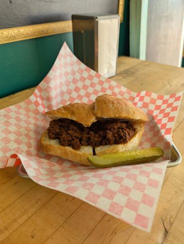 A fried chicken sandwich with a pickle on checkered paper.