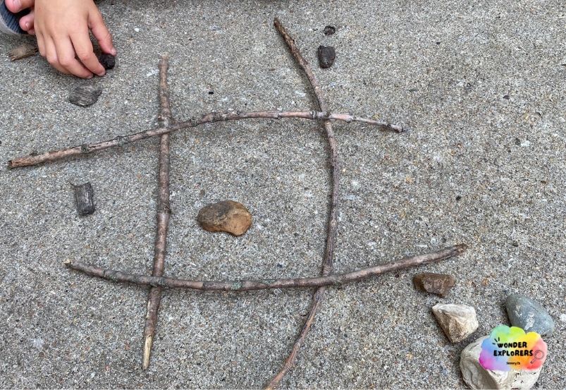 Nature tic-tac-toe with sticks, rocks, and mulch