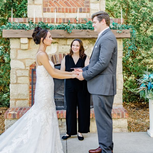 Bride and groom holding hands during outdoor wedding ceremony.