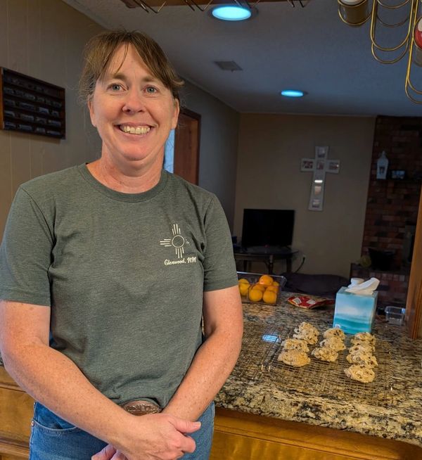 Woman smiling in kitchen with cookies on counter.