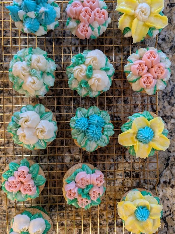 Decorative flower-themed cupcakes on a cooling rack.