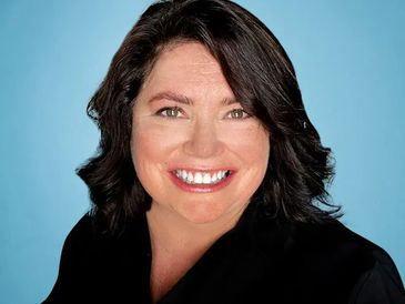 Smiling woman with dark hair against a blue background.
