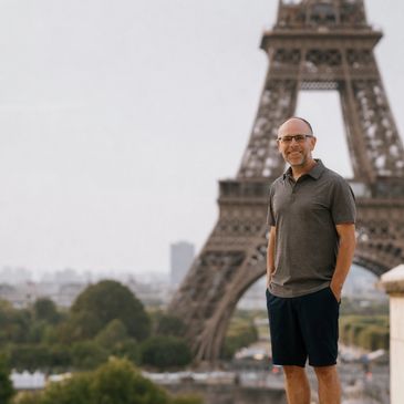 A man smiling in front of the Eiffel Tower in Paris.