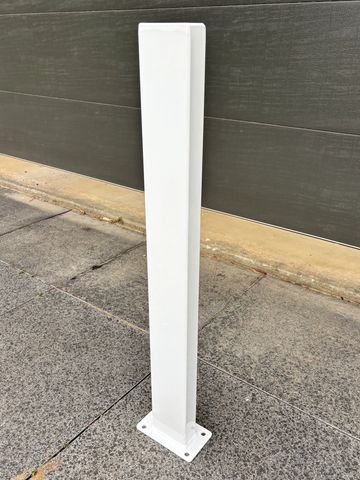 White metal bracket mounted on a wall outdoors.