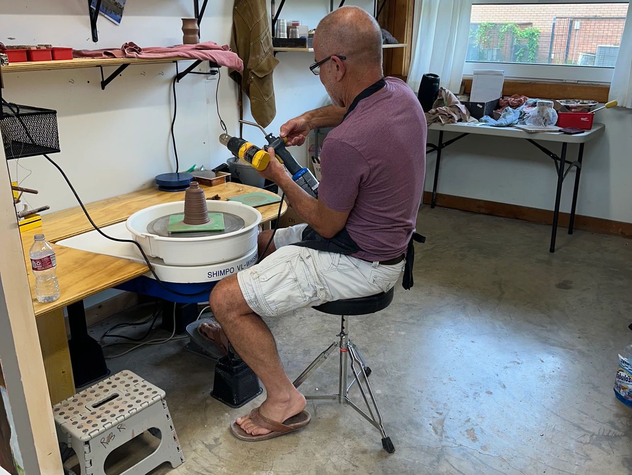 Man working on pottery wheel using a torch.