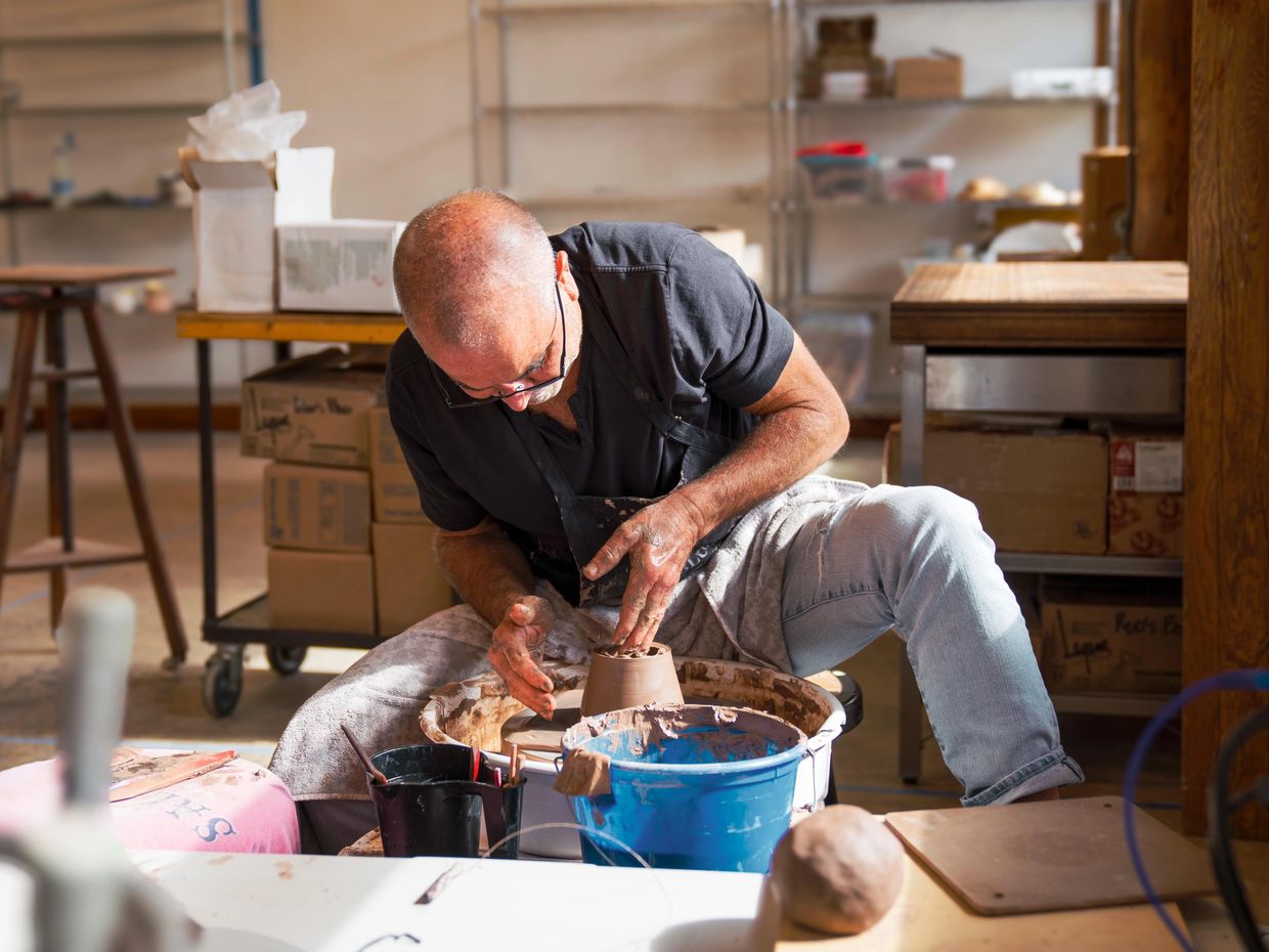 Man shaping clay on a pottery wheel.