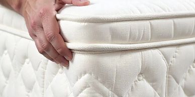 Hands adjusting a white quilted mattress corner.