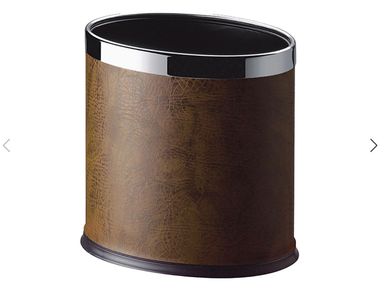Brown leather and metal wastebasket with an oval top.