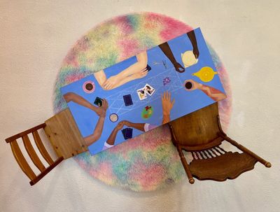 Top-down view of a colorful table scene with hands, drinks, and two wooden chairs.