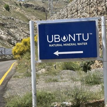 Sign for Ubuntu natural mineral water with a left arrow in a mountainous area.