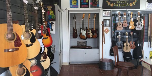 A music store showcasing guitars and ukuleles neatly displayed on walls.