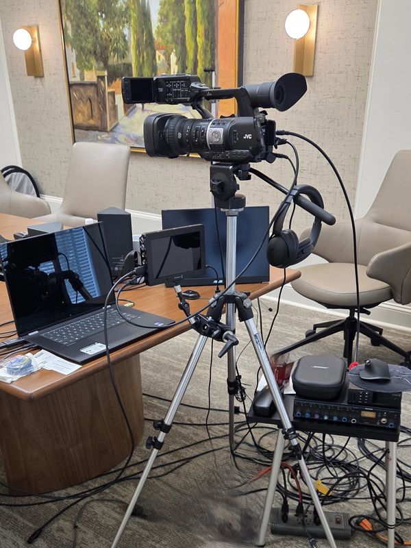 Video camera setup on a tripod in an office.