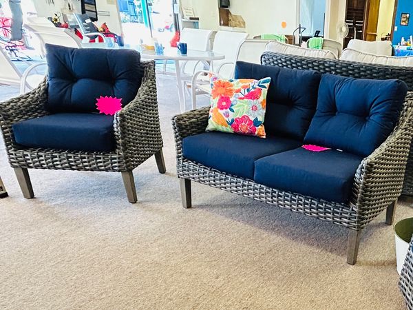 Wicker patio furniture with navy cushions in a showroom.