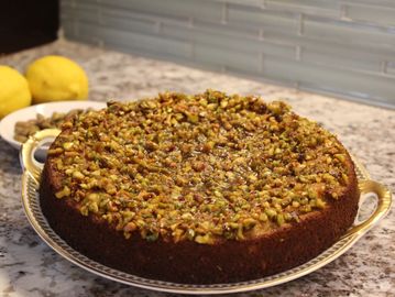 A round cake topped with a generous layer of chopped nuts on a kitchen counter.