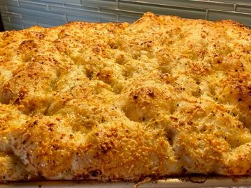 Golden, cheesy baked focaccia bread with a crispy crust.