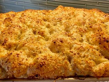 Golden, cheesy baked focaccia bread with a crispy crust.