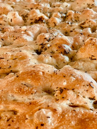 Close-up of freshly baked herb focaccia bread.